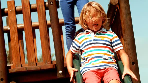 Schoolboy enjoying while playing on slide