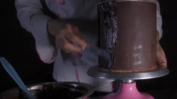 chef smearing chocolate topping on a cake