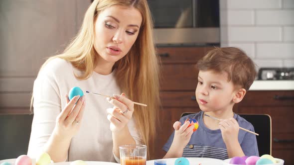 Woman Decorating Easter Eggs with Little Son