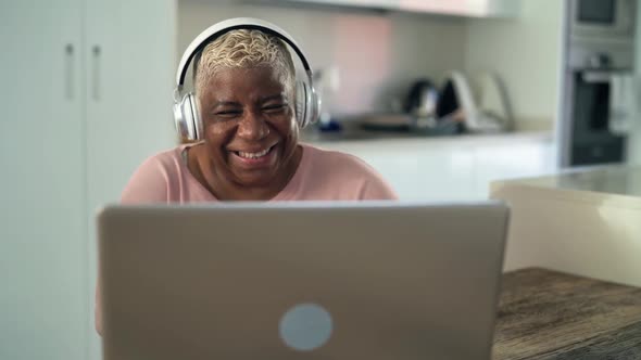 Happy senior woman having fun doing video call using laptop at home