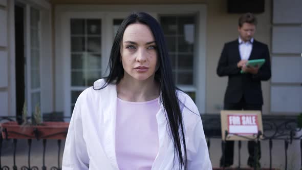 Front View Portrait of Confident Caucasian Serious Woman Looking Around Standing in Front of House