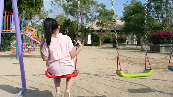 Sad Asian Girl Playing Swing In The Park