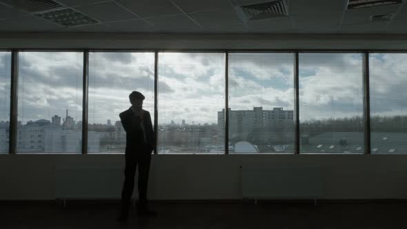 Waiting Process Businessman Walks in Front of a Panoramic Window Morning in a Modern Office Natural