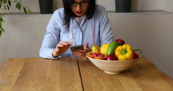 Nutritionist woman with healthy fruit and vegetable using smartphone