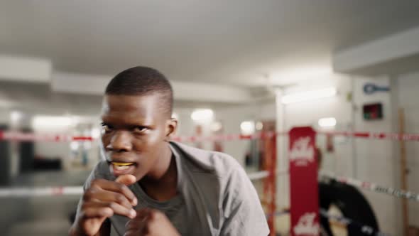 Young Motivated African Sportsman Boxer Throwing Punches at Camera During Boxing Training in Gym