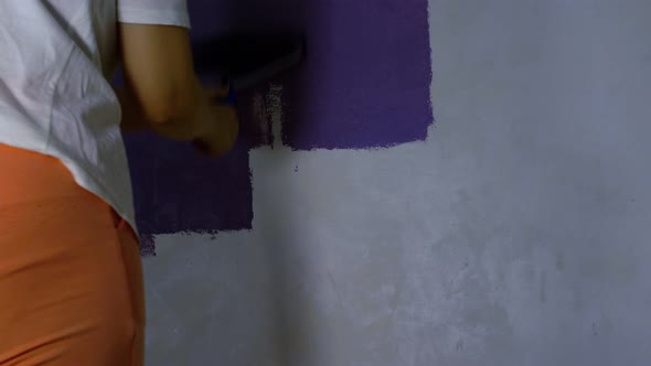 Close Up of Woman's Hand in Protective Glove Painting Wall in Purple Colour with Roller