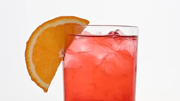 Adding straw to glass of pink cocktail over white