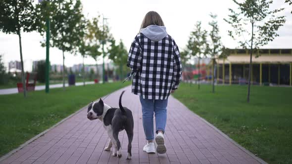 Back View Young Caucasian Woman in Eyeglasses Strolling with Dog Turning Laughing