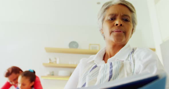 Grandmother reading recipe book in kitchen