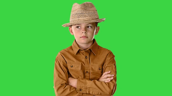 Boy in a Shirt and Straw Hat Posing with Crossed Arms and Then Putting Arms on His Hips on a Green