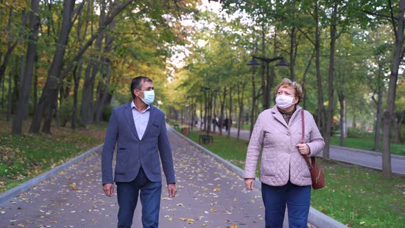 Middle Aged Couple in Masks Walking in Autumn Park