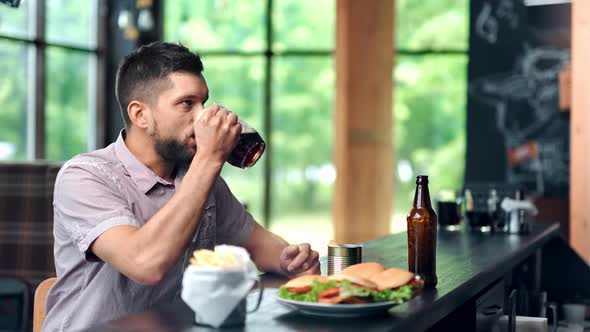 Carefree Young Man Watching Championship at Sport Bar Having Beer and Fast Food Medium Shot