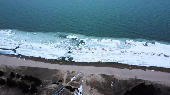 Parallax 4K drone video of a beach with frozen shoreline