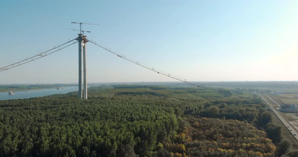 Main Tower Of Braila Bridge Stands Between Danube River And County Road In Romania. aerial, forward