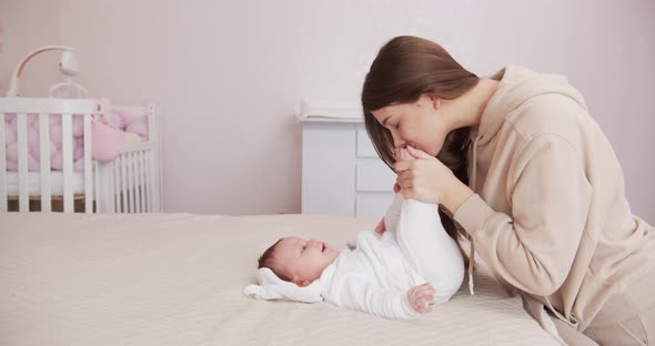 A Loving Mother Tenderly Kisses Her Baby's Little Legs. Maternal Love.