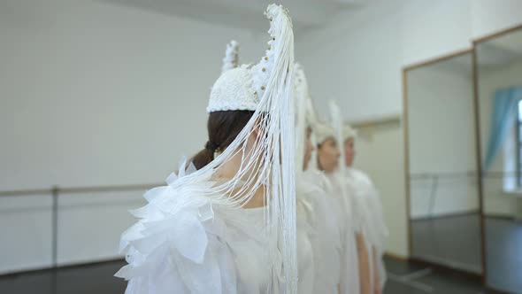 Talented Dancers in White Angel Costumes Turning to Camera Rehearsing Performance in Studio