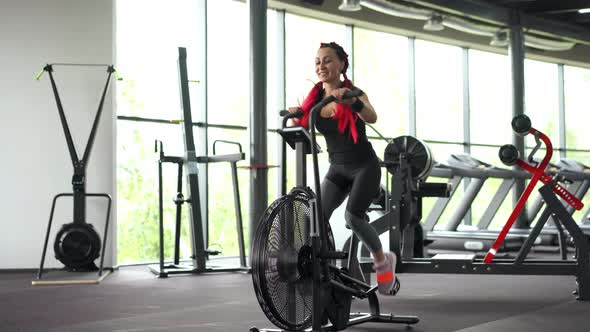 Woman Exercise Bike Gym Cycling Training Fitness. Fitness Male Using Air Bike Cardio Workout. 