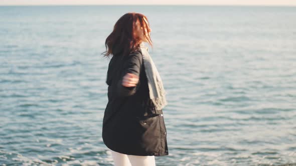 Young Beautiful Woman Walks and Enjoys the Sea on a Warm Winter Day