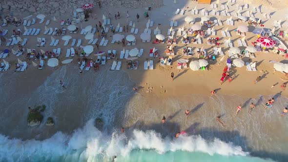 People Swim on Light Blue Sea in the White Sandy Beach Near the Rocky Mountainside