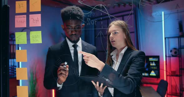 Businesspeople which Standing Near Glass Wall and Discussing Joint Business Strategy Drawing