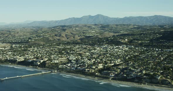 Helicopter aerial shot moving past monotonous white homes onto California highway, sunny day