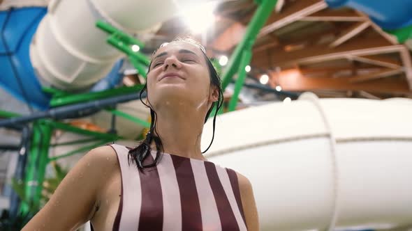 Attractive Young Woman Relaxing in a Large Water Park Looking Around and Enjoying the Sun Glare