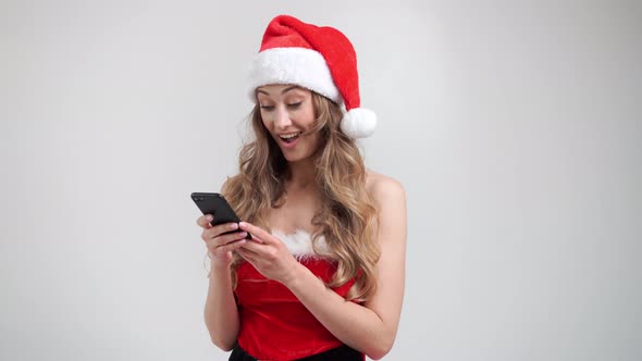 Woman Christmas Santa Hat White Studio Background with Smartphone in Hand