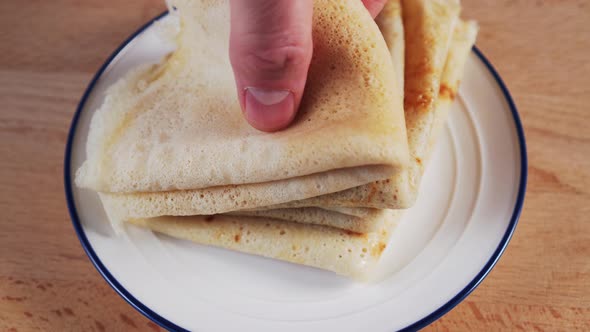 A hand picks up a freshly baked, porous pancake