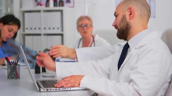 Doctor Typing on Laptop Research Informations While Teamworkers Discussing