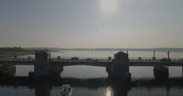 Sun Shining on Cars Driving on Small Bridge while Speedboat Passes Under