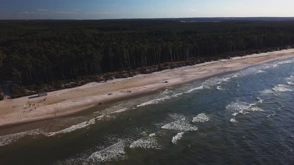 Drone footage of a sandy beach and pine forrest. Sunny day, Baltic Sea, Lubiatowo, Poland.