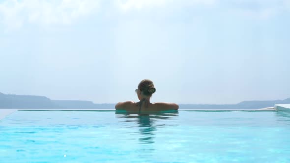 Young Woman Relaxing in the Pool with a Gorgeous View on Santorini