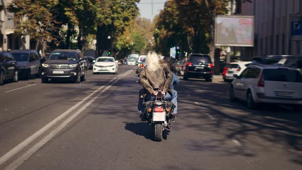 Two Women Riding Motorcycle By the City Street Rear View