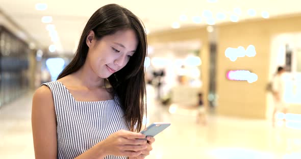 Woman looking at smart phone in shopping mall