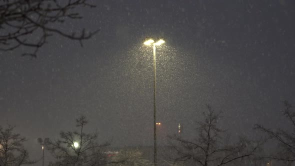 Snow falling lit up by parking lot light during winter storm