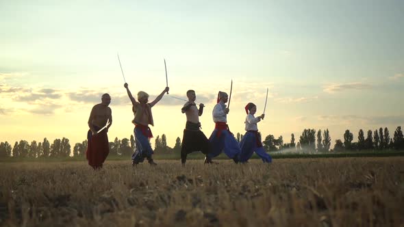 Group of Cossack Men in Traditional Clothes Swinging and Spinning Sharp Shashkas Against Cloudy