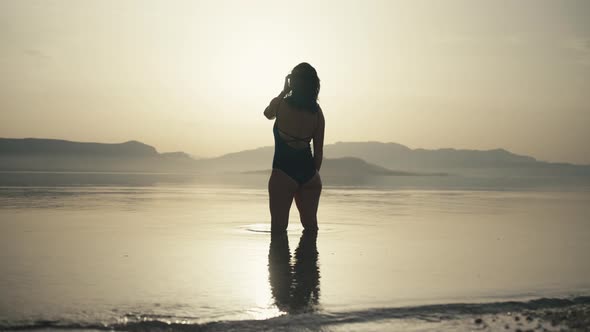 The Girl Stands in the Ocean Water and Raises Her Hands