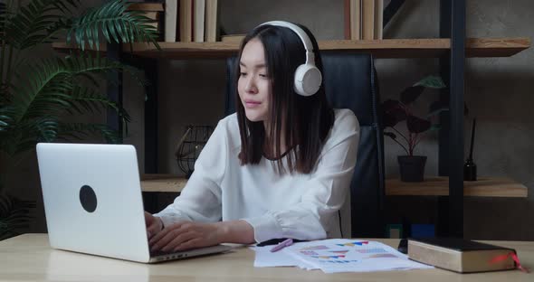 Tired Young Asian Business Woman Wearing Headphones Communicating End of the Working Day