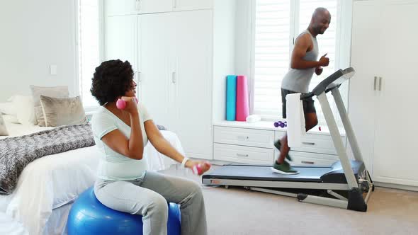 Woman exercising with dumbbells while man jogging on treadmill 4k