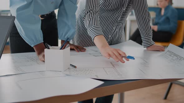 Close Up of Architects Analyzing Blueprints Plans on Table