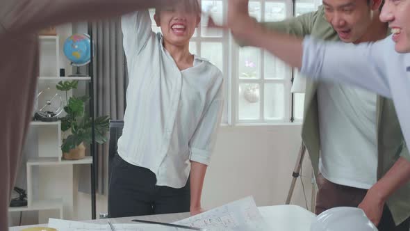 Group Of Asian Engineers Create Harmony With Hands On Top Of Each Other At The Office