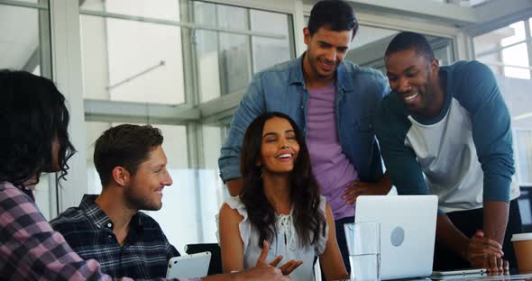 Happy executives discussing over laptop