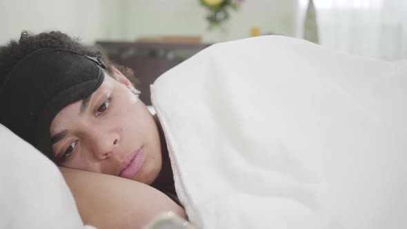 Close-up View of Attractive African American Woman Lying Under White Blanket with Black Sleeping