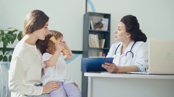 Mother With Kid at Visiting Pediatrician.Talking With a Doctor At Consultation During an Appointment