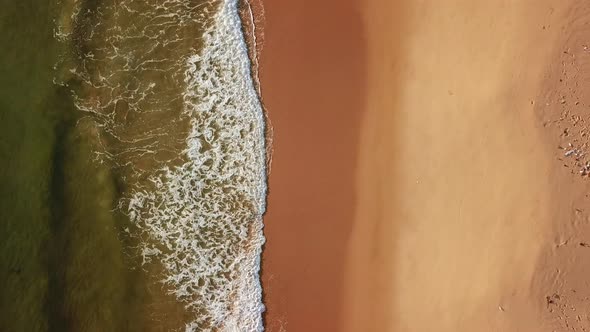 Drone View of Sea Foam Waves, Beating Against Sandy Seashore.