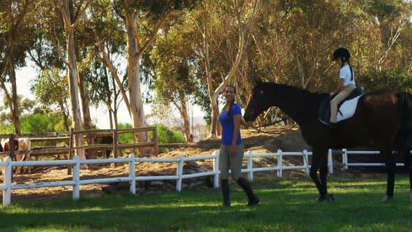 Mother assisting daughter during horse riding 4k