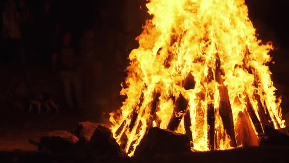 People Around a Large Bonfire at a Night Party. Slow Motion. Big Fire Background