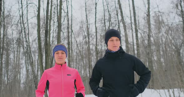 Positive Beautiful Young Healthy Couple Running with Sportswear Through the Forest