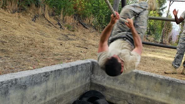 Military soldier climbing rope during obstacle course