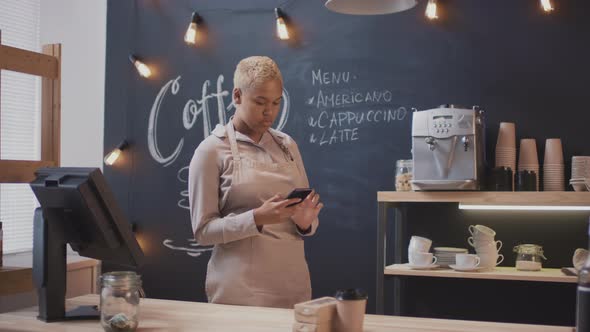 African American Cafe Worker With Smartphone